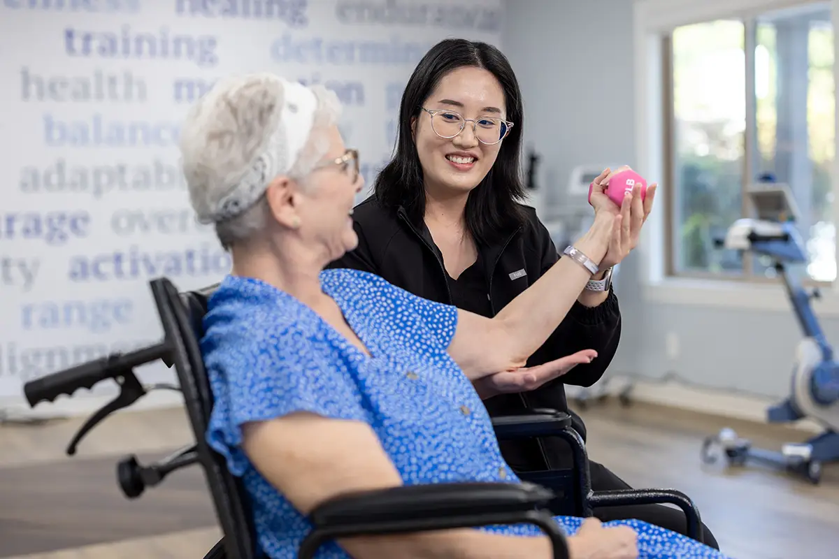A physical therapist helping an elderly woman lift weights at Sunnyvale Post Acute